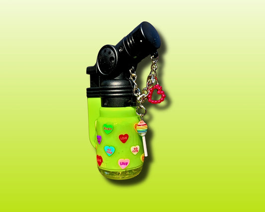 Green lighter with colorful heart designs and a keychain on a light green background